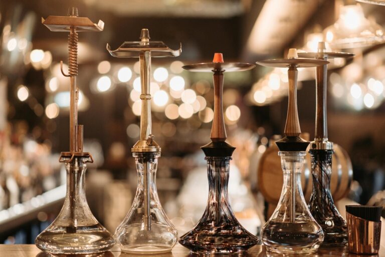 A collection of elegant hookahs displayed on a bar counter, accented by warm bokeh lights.