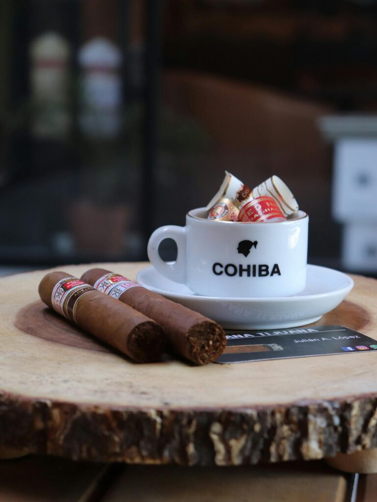 A cup filled with cigar bands and Cohiba cigars on a rustic wooden slice table.